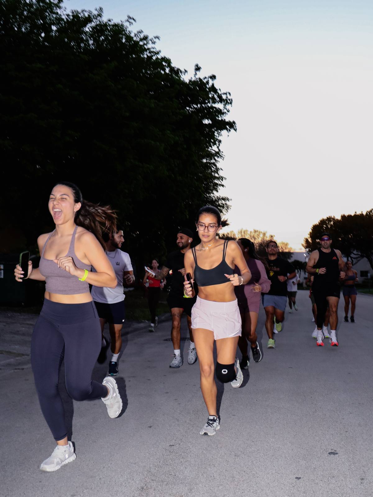 Two runners laughing mid-run at dusk